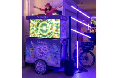 Une DJ joue de la musique sur une scène mobile montée sur un vélo, dans une cour extérieure.