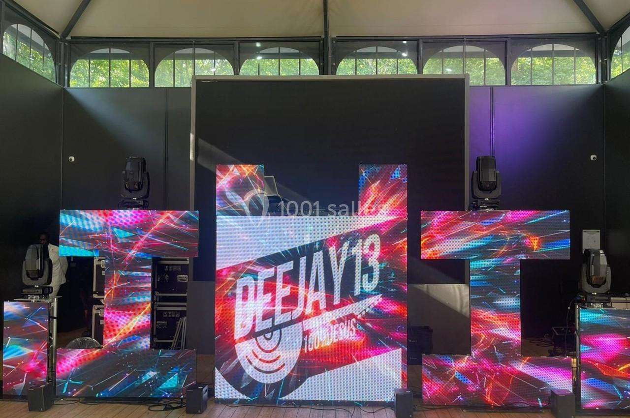 Structure lumineuse avec écrans LED affichant des motifs colorés et le texte ’DEEJAY 13’ dans un espace intérieur.