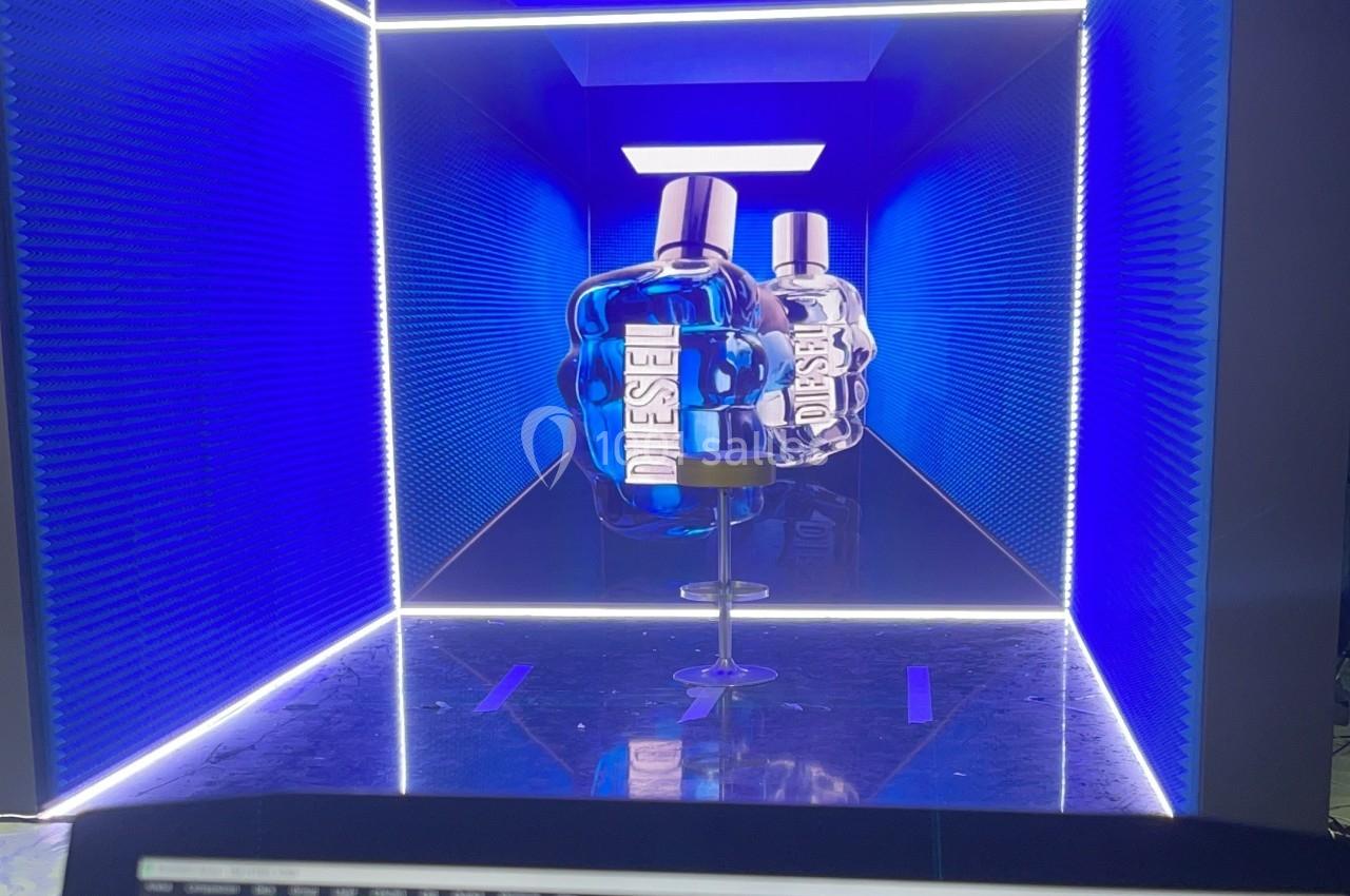 Deux flacons de parfum Diesel bleus exposés dans un couloir lumineux aux parois texturées et éclairage néon.