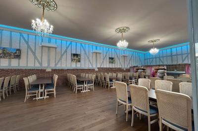 Salle lumineuse avec des tables en bois, des chaises en osier et de grandes fenêtres donnant sur une terrasse extérieure.