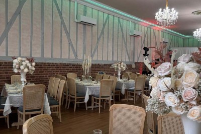 Salle lumineuse avec des tables en bois, des chaises en osier et de grandes fenêtres donnant sur une terrasse extérieure.