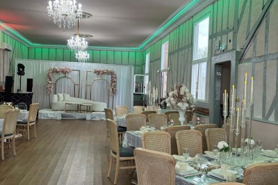 Salle lumineuse avec des tables en bois, des chaises en osier et de grandes fenêtres donnant sur une terrasse extérieure.
