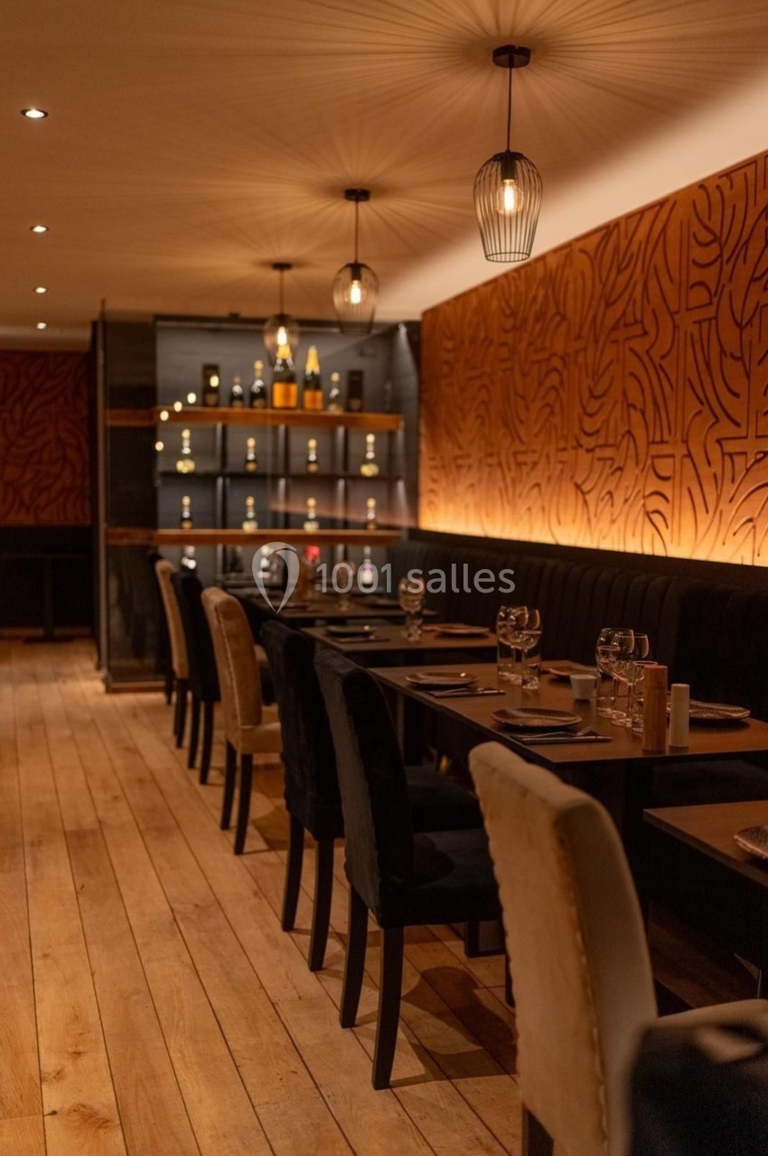 Salle de restaurant chaleureuse avec tables dressées, éclairage tamisé et décoration murale en bois sculpté.