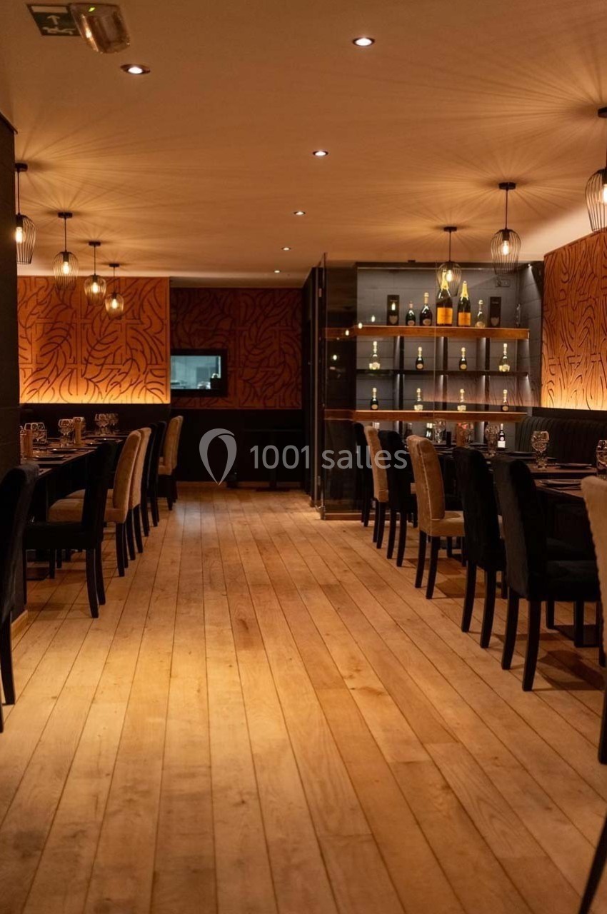 Salle de restaurant élégante avec parquet en bois clair, tables dressées et éclairage tamisé.
