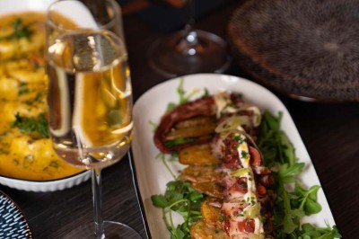 Assortiment de plats variés comprenant légumes, tartines, salade, samoussas et sauce, disposés sur une table sombre.