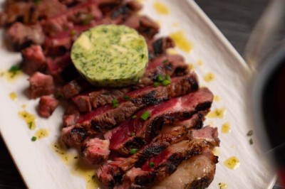 Assortiment de plats variés comprenant légumes, tartines, salade, samoussas et sauce, disposés sur une table sombre.