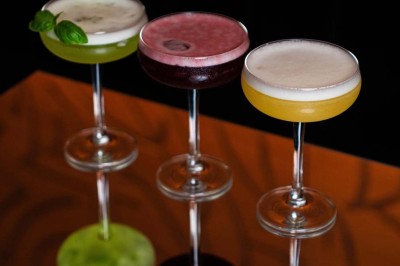 Assortiment de plats variés comprenant légumes, tartines, salade, samoussas et sauce, disposés sur une table sombre.