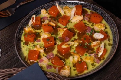 Assortiment de plats variés comprenant légumes, tartines, salade, samoussas et sauce, disposés sur une table sombre.