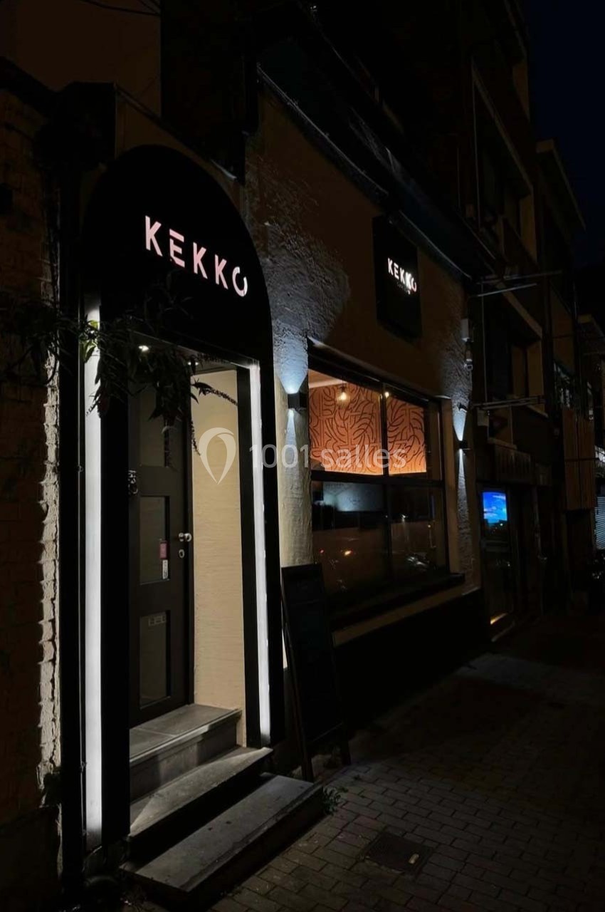 Façade d'un restaurant éclairé la nuit, avec une enseigne lumineuse ’Kekko’ et une vitrine donnant sur l'intérieur.