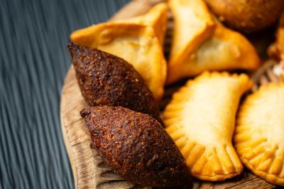 Assortiment de beignets et pâtisseries salées disposés sur un plateau en bois.