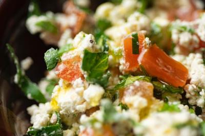 Salade composée de tomates, fromage frais, herbes fraîches et assaisonnement, vue en gros plan.