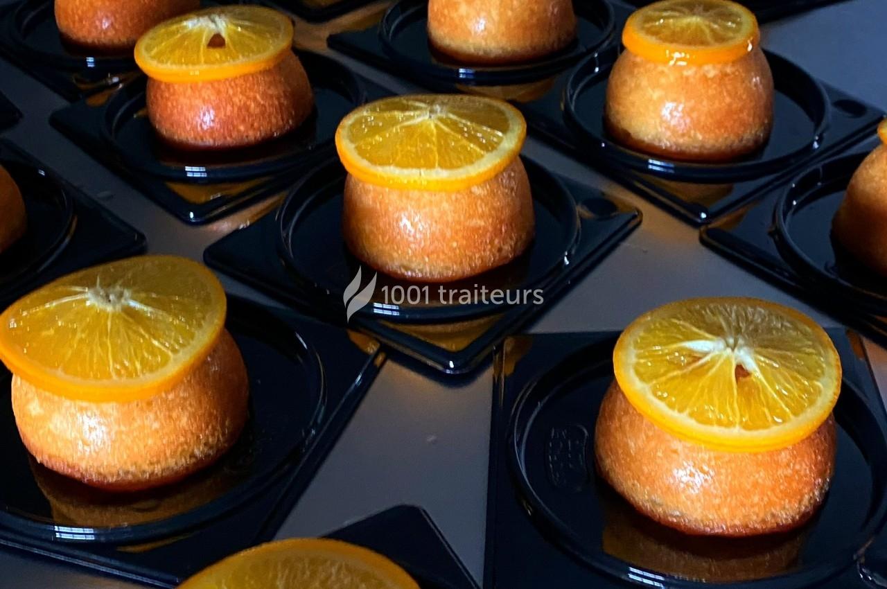 Des gâteaux individuels garnis de tranches d'orange disposés sur des plateaux noirs.