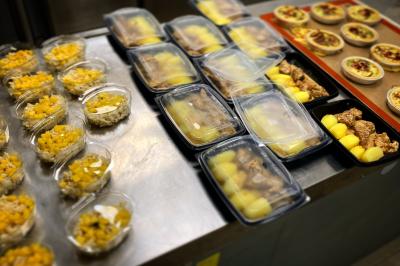 Repas préparés disposés sur un plan de travail, comprenant salades, plats principaux et desserts emballés.