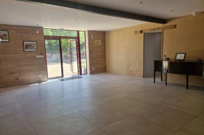 Cour extérieure ensoleillée avec des tentes noires, des fleurs en pot et une maison en pierre en arrière-plan.