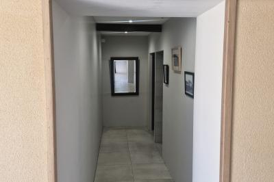 Cour extérieure ensoleillée avec des tentes noires, des fleurs en pot et une maison en pierre en arrière-plan.