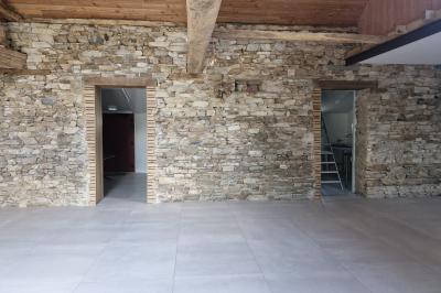 Cour extérieure ensoleillée avec des tentes noires, des fleurs en pot et une maison en pierre en arrière-plan.