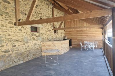 Cour extérieure ensoleillée avec des tentes noires, des fleurs en pot et une maison en pierre en arrière-plan.