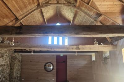 Cour extérieure ensoleillée avec des tentes noires, des fleurs en pot et une maison en pierre en arrière-plan.