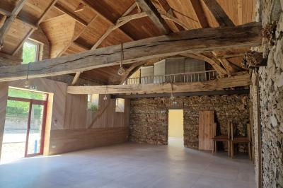 Cour extérieure ensoleillée avec des tentes noires, des fleurs en pot et une maison en pierre en arrière-plan.