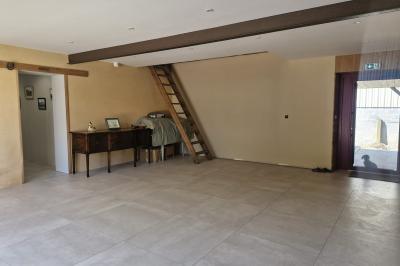 Cour extérieure ensoleillée avec des tentes noires, des fleurs en pot et une maison en pierre en arrière-plan.