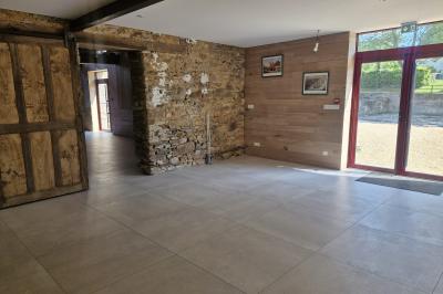 Cour extérieure ensoleillée avec des tentes noires, des fleurs en pot et une maison en pierre en arrière-plan.