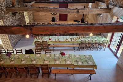 Cour extérieure ensoleillée avec des tentes noires, des fleurs en pot et une maison en pierre en arrière-plan.