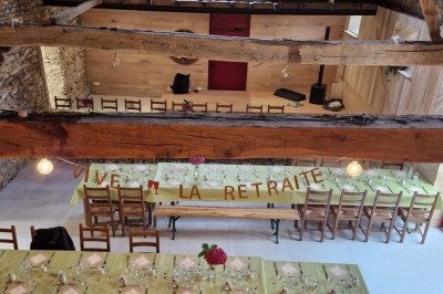 Cour extérieure ensoleillée avec des tentes noires, des fleurs en pot et une maison en pierre en arrière-plan.