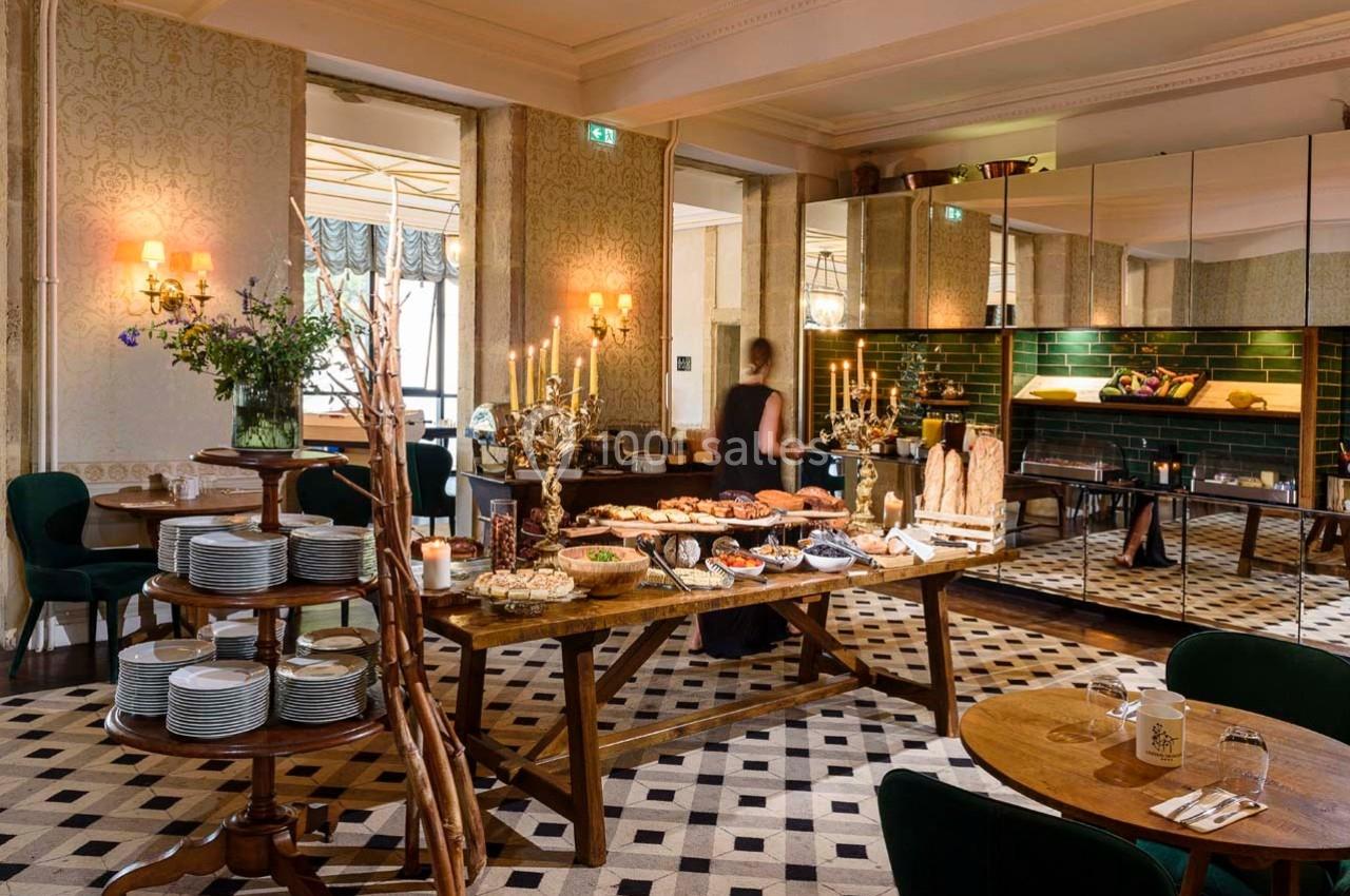 Salle de restaurant élégante avec buffet garni de plats variés, décorée de chandeliers et de miroirs.