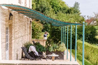 Salle de bain lumineuse avec vasque blanche, serviettes pliées et vue sur un jardin à travers une porte-fenêtre.