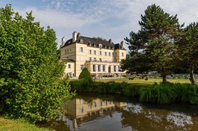 Salle de bain lumineuse avec vasque blanche, serviettes pliées et vue sur un jardin à travers une porte-fenêtre.