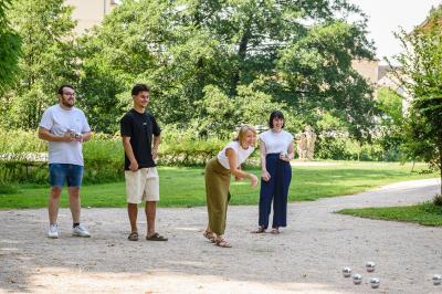 Salle de bain lumineuse avec vasque blanche, serviettes pliées et vue sur un jardin à travers une porte-fenêtre.