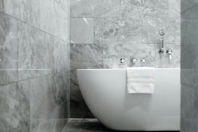 Salle de bain lumineuse avec vasque blanche, serviettes pliées et vue sur un jardin à travers une porte-fenêtre.