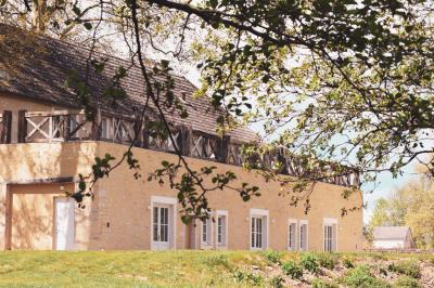 Salle de bain lumineuse avec vasque blanche, serviettes pliées et vue sur un jardin à travers une porte-fenêtre.