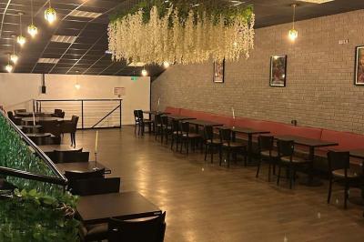 Salle moderne avec écran affichant des cœurs lumineux, tables et chaises noires, plafond décoré de fleurs suspendues.