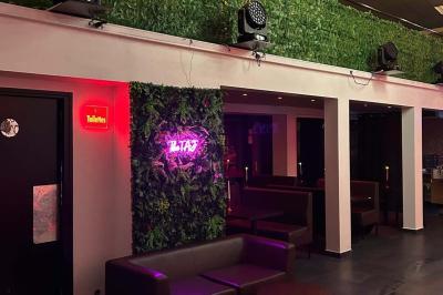 Salle moderne avec écran affichant des cœurs lumineux, tables et chaises noires, plafond décoré de fleurs suspendues.