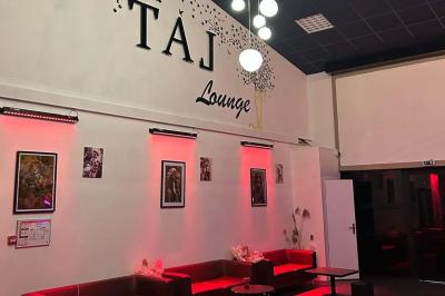 Salle moderne avec écran affichant des cœurs lumineux, tables et chaises noires, plafond décoré de fleurs suspendues.