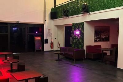 Salle moderne avec écran affichant des cœurs lumineux, tables et chaises noires, plafond décoré de fleurs suspendues.