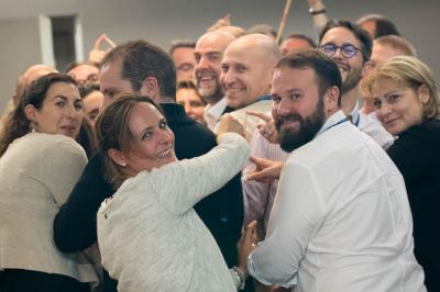Un groupe de personnes souriantes rassemblées dans une ambiance conviviale lors d'un événement en intérieur.