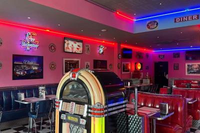 Intérieur d'un diner rétro avec banquettes rouges, sol en damier noir et blanc, et décoration vintage.