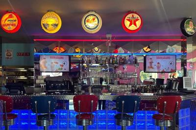 Intérieur d'un diner rétro avec banquettes rouges, sol en damier noir et blanc, et décoration vintage.