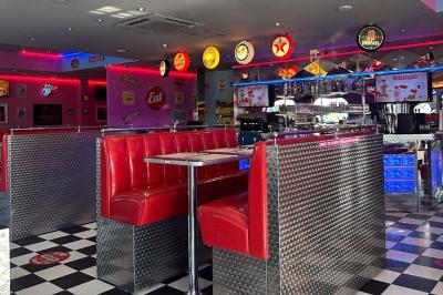 Intérieur d'un diner rétro avec banquettes rouges, sol en damier noir et blanc, et décoration vintage.