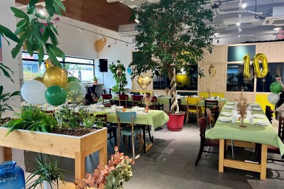 Personne disposant des verrines individuelles garnies de crumble sur un plateau dans une cuisine professionnelle.