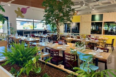 Personne disposant des verrines individuelles garnies de crumble sur un plateau dans une cuisine professionnelle.