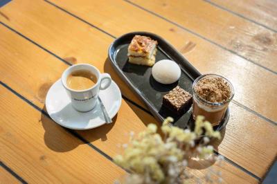 Miniature Café gourmand Minutes Papillons Personne disposant des verrines individuelles garnies de crumble sur un plateau dans une cuisine professionnelle.