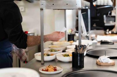 Miniature Cuisine Minutes Papillons Personne disposant des verrines individuelles garnies de crumble sur un plateau dans une cuisine professionnelle.
