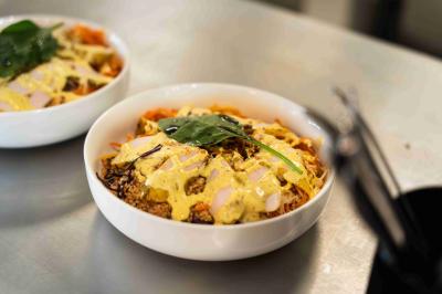 Miniature Menu cuisine Minutes Papillons Personne disposant des verrines individuelles garnies de crumble sur un plateau dans une cuisine professionnelle.