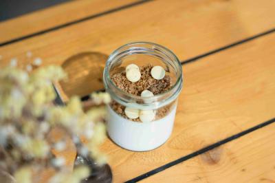 Miniature Verrine dessert Minutes Papillons Personne disposant des verrines individuelles garnies de crumble sur un plateau dans une cuisine professionnelle.