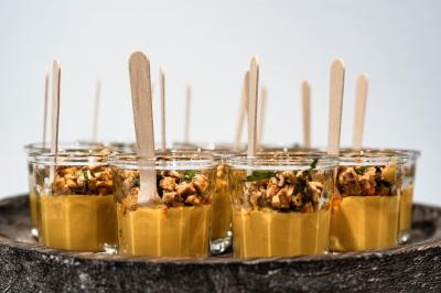 Miniature Verrines traiteur Minutes Papillons Personne disposant des verrines individuelles garnies de crumble sur un plateau dans une cuisine professionnelle.