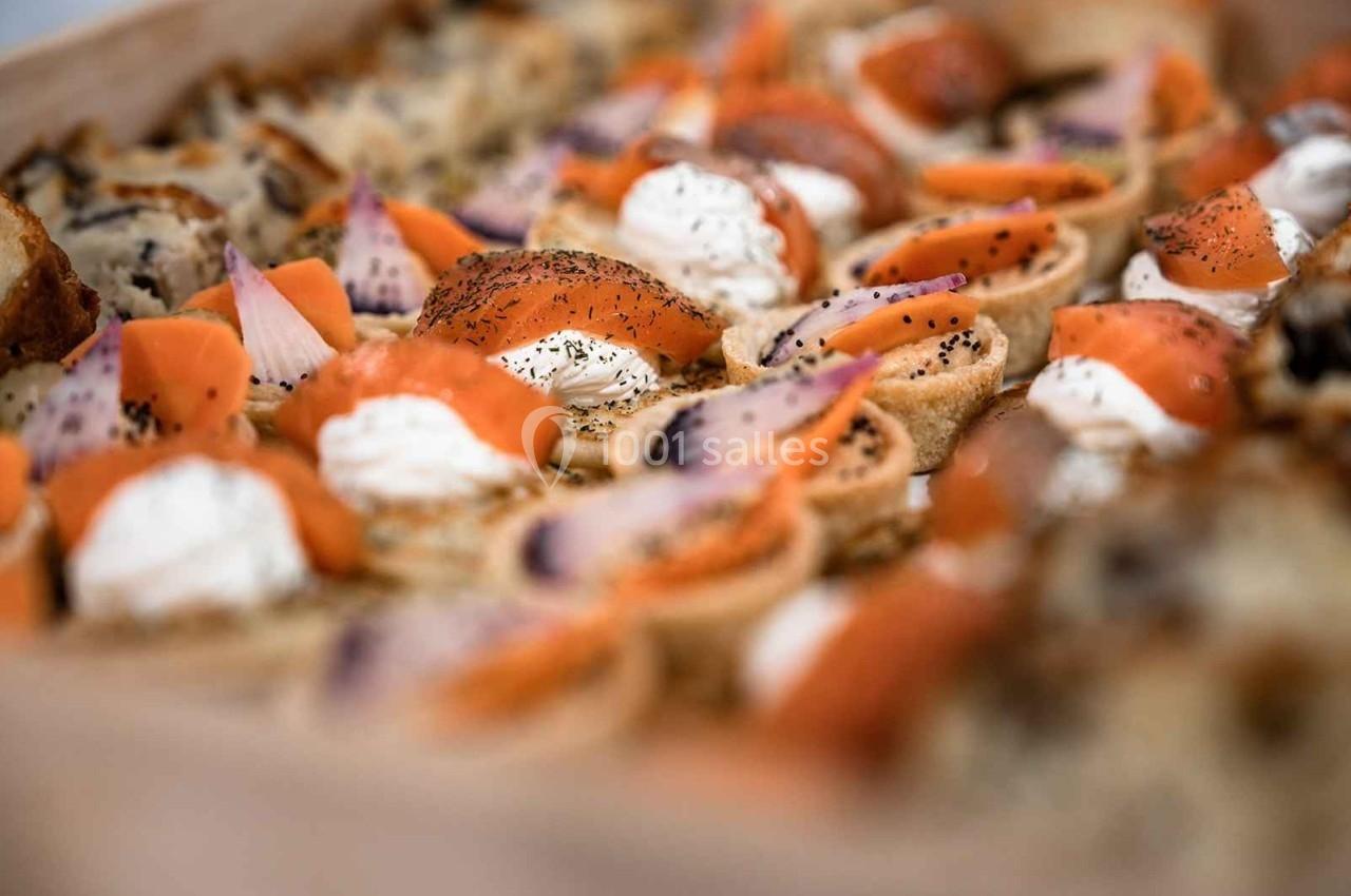Assortiment de canapés garnis de saumon fumé, crème fraîche et herbes, disposés sur un plateau.