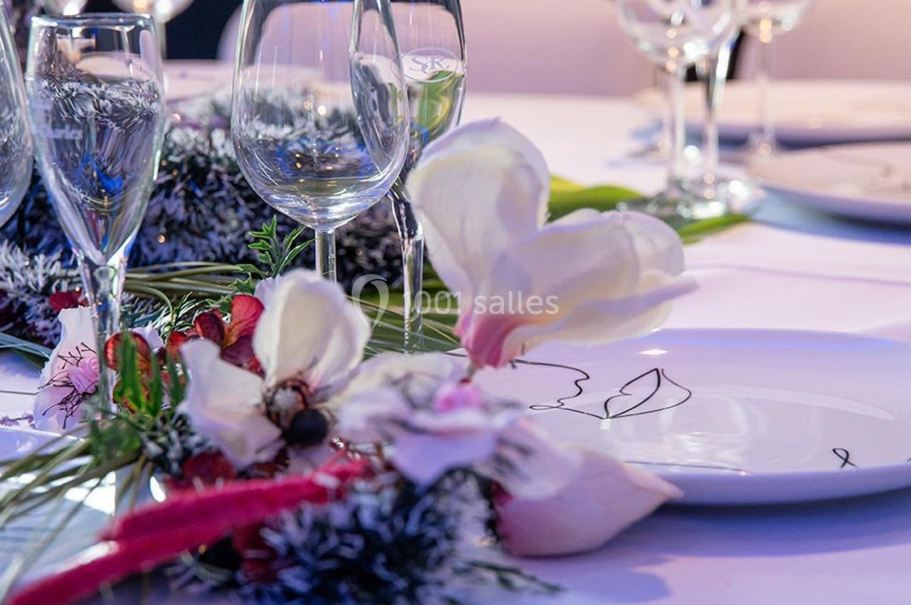Table dressée avec des verres à vin, des assiettes décorées et une composition florale élégante.